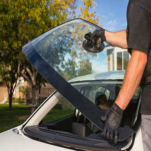 A technician replacing the windshield on a passenger car.